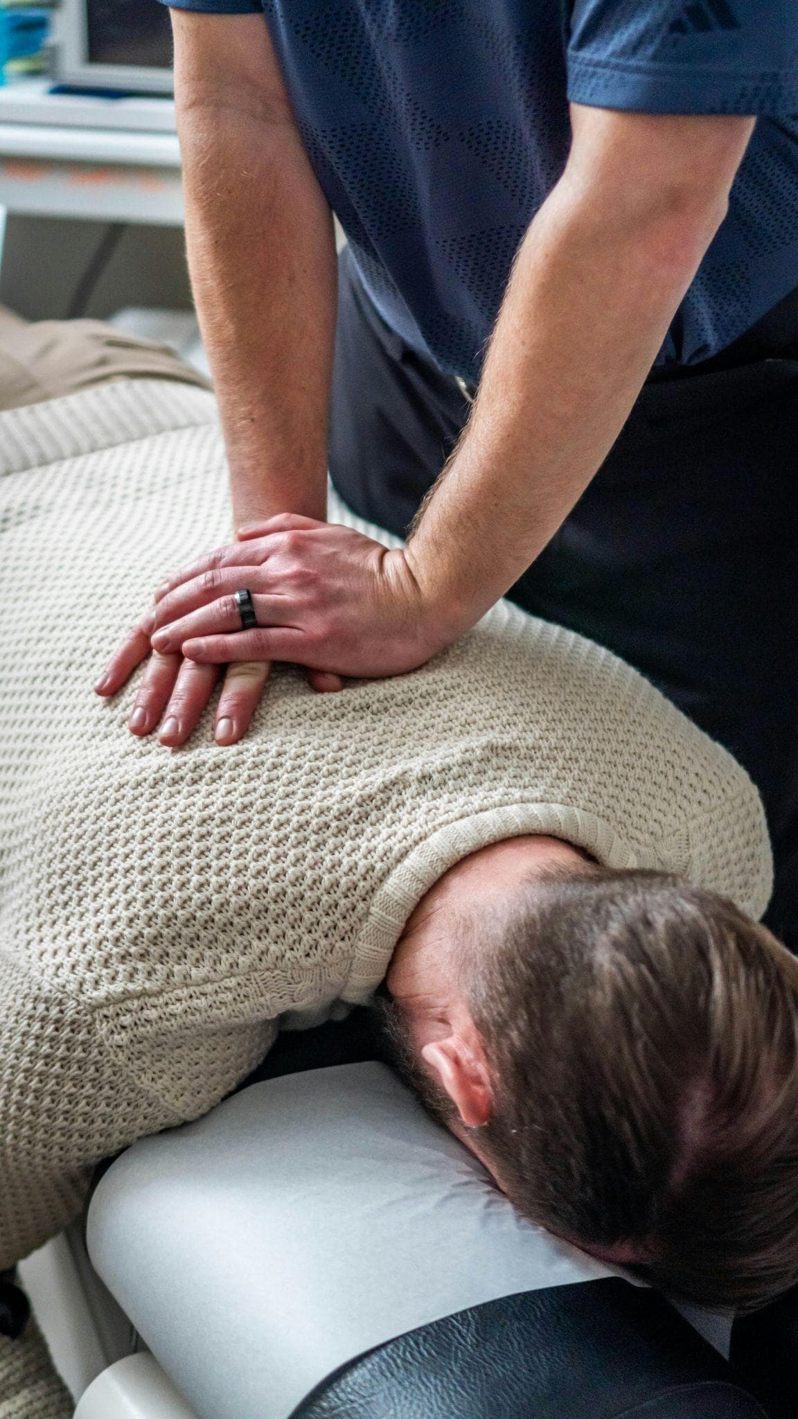 Hands applying pressure to a patient's upper back during treatment